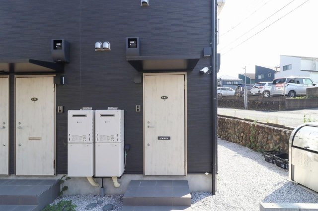 アトリアコートⅣ101号室 玄関右側には防犯カメラを設置 建物の右側にゴミ置き場もあり