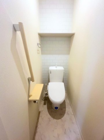 ラパンドール 温水洗浄機能つき便座。トイレ内には収納棚あり。